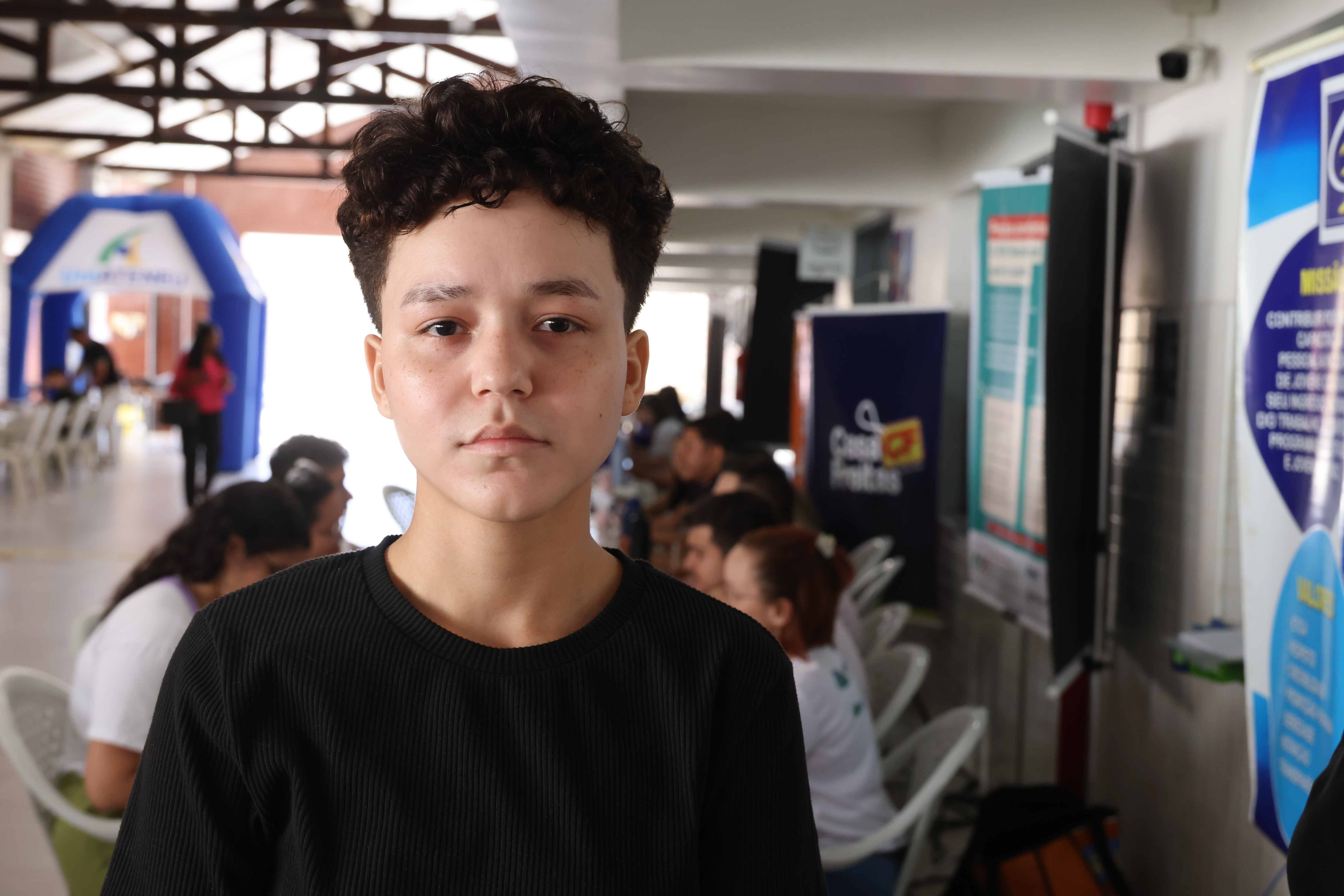 Ana Leticia posa para a foto, ela é branca, tem cabelo curto, usa óculos e veste blusa preta